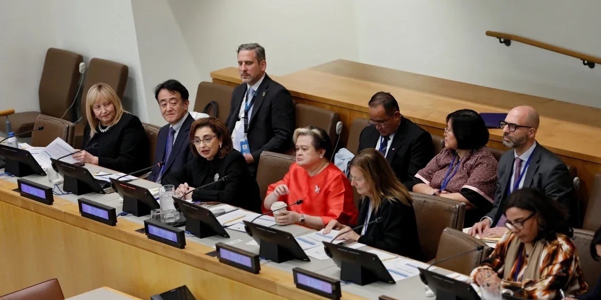 A large panel of speakers in a United Nations conference room